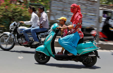 A woman shields her face from the sun as she rides her scooter in Ahmedabad, India May 20, 2016. REUTERS/Amit Dave