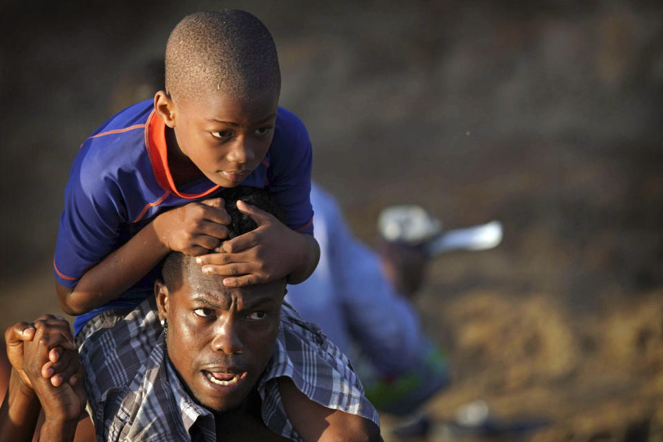 A man carries a boy across the Rio Grande river as migrants, many from Haiti, leave Del Rio, Texas to return to Ciudad Acuna, Mexico, early Wednesday, Sept. 22, 2021, some to avoid possible deportation from the U.S. and others to load up on supplies. (AP Photo/Fernando Llano)