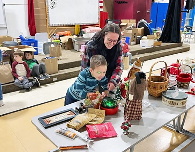 Gonic Elementary School Kindergartener Corey Olsen gets some help from Paraprofessional McKenzie Clark while shopping for his family at a free family shopping spree held for students.