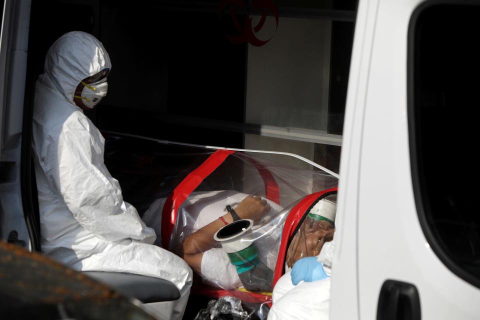 A paramedic, wearing protective suit and mask, transports a man suspected of being infected with the coronavirus in Mexico City in April.