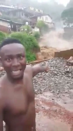 Kelvin Kamara speaks to the camera as he gestures to gushing water in the town of Foulah, following a mudslide on the outskirts of Freetown, Sierra Leone, in this still image obtained from a social media video taken August 14, 2017. Video taken August 14, 2017. Kelvin Kamara and Fuhard Sesay / Social Media Website via REUTERS.