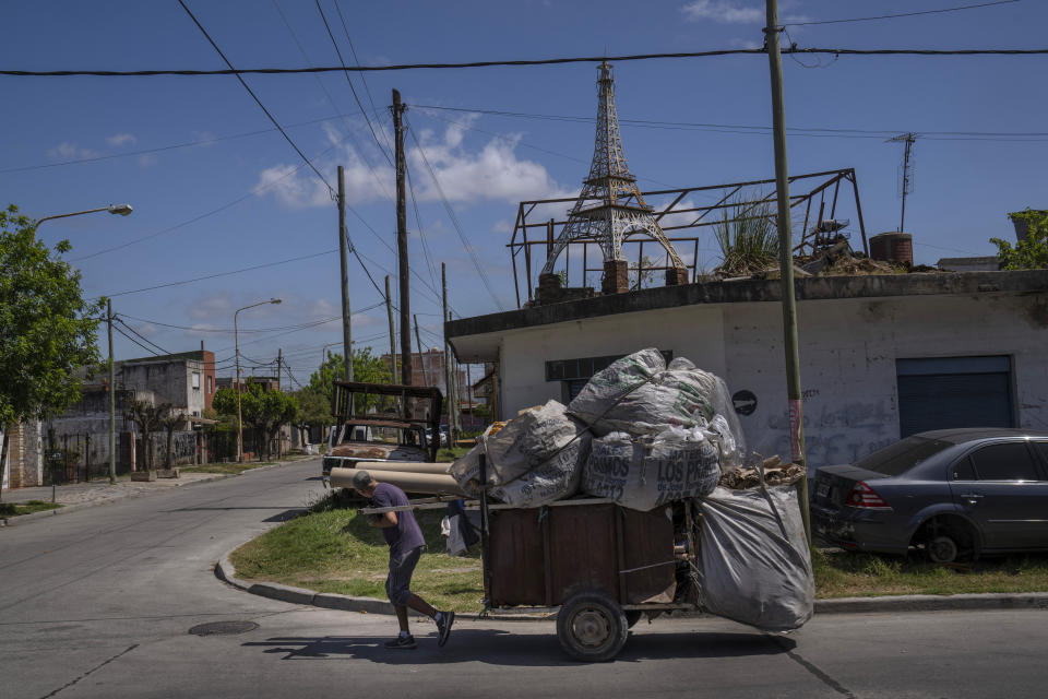 Un reciclador de cartón tira de su carrito frente a la casa de Miguel Muñoz, donde una réplica de la Torre Eiffel se encuentra en un techo, elevada sobre una pila de ladrillos, en La Tablada, Argentina, el martes 18 de octubre de 2022. (AP Foto/Rodrigo Abd)