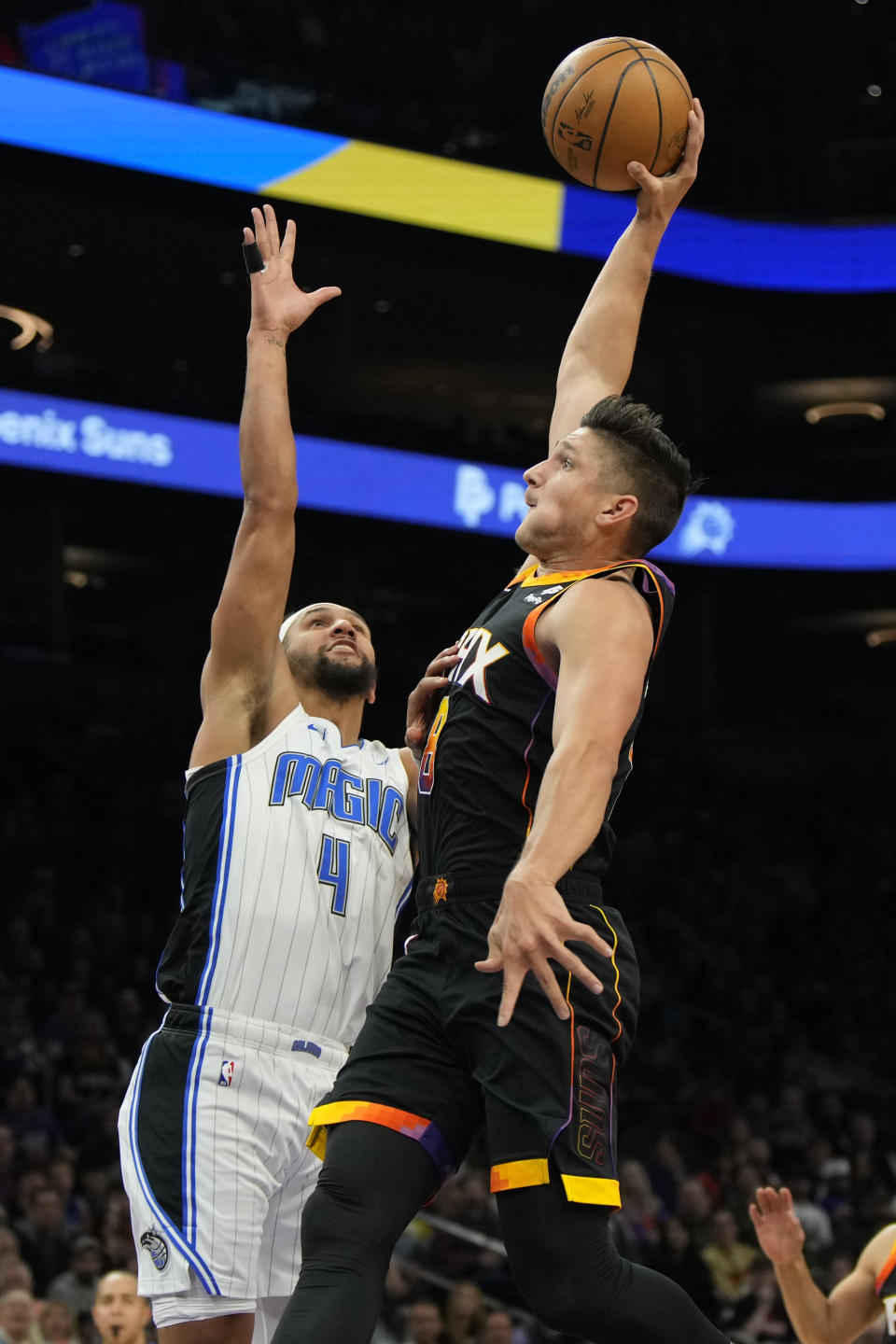 Phoenix Suns guard Grayson Allen, right, shoots over Orlando Magic guard Jalen Suggs (4) during the first half of an NBA basketball game, Sunday, Dec. 31, 2023, in Phoenix. (AP Photo/Rick Scuteri)