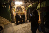 Christians take photos inside the Grotto of the Church of the Nativity, traditionally believed to be the birthplace of Jesus Christ, in the West Bank city of Bethlehem, Monday, Nov. 23, 2020. Normally packed with tourists from around the world at this time of year, Bethlehem resembles a ghost town – with hotels, restaurants and souvenir shops shuttered by the pandemic. (AP Photo/Majdi Mohammed)