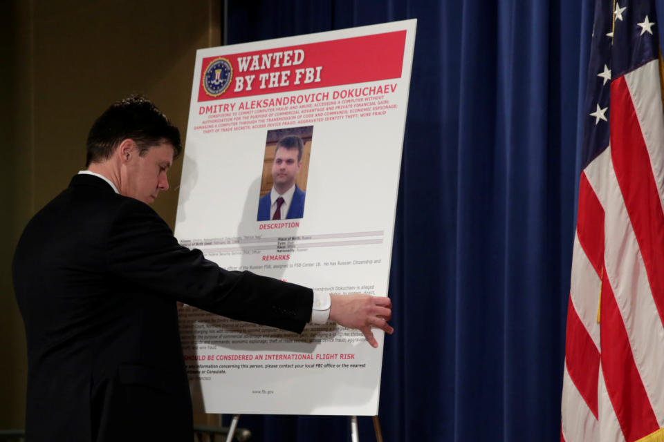 Department of Justice staffer installs a poster of a suspected Russian hacker before FBI National Security Division and the U.S. Attorney's Office for the Northern District of California joint news conference at the Justice Department in Washington, U.S., March 15, 2017. REUTERS/Yuri Gripas