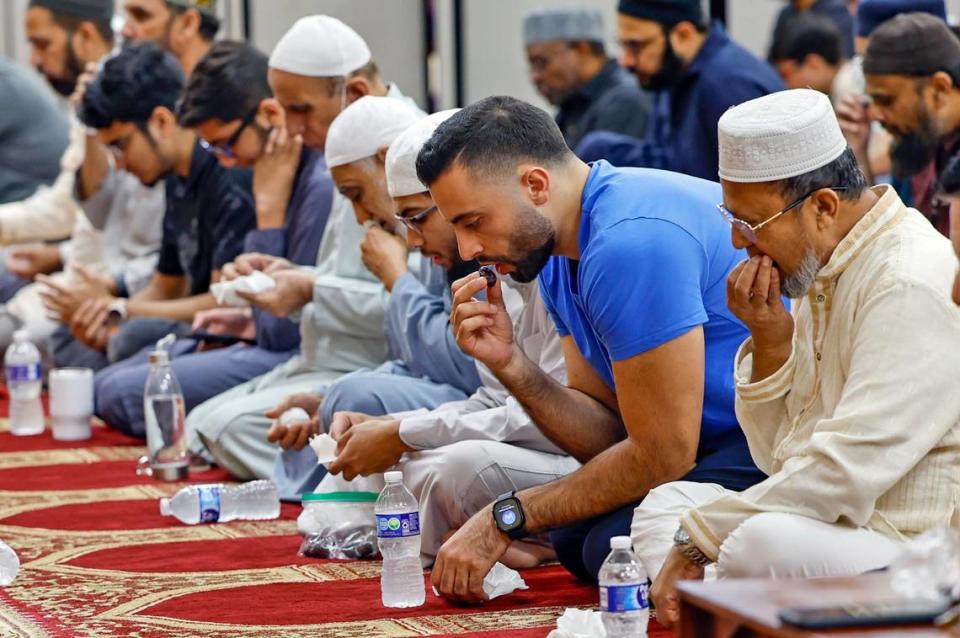 Abdallah Hasouneh, wearing a blue shirt, joins others as they end their fast on the Day of Arafah eating dates and drinking water. Al Diaz/adiaz@miamiherald.com