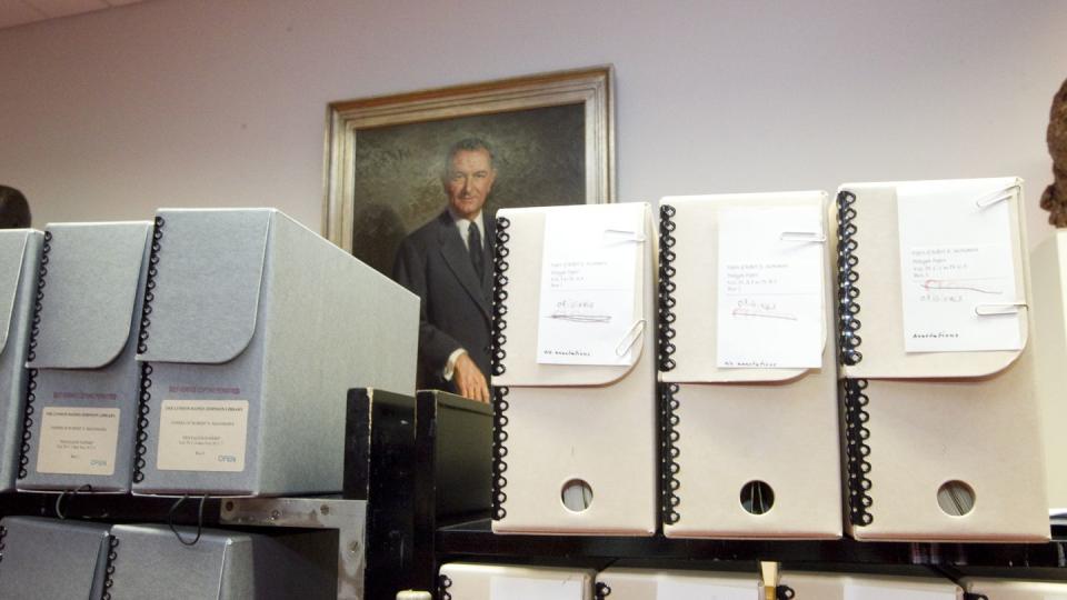 file folders rest on black shelves in front of a portrait of lyndon b johnson hanging on a wall