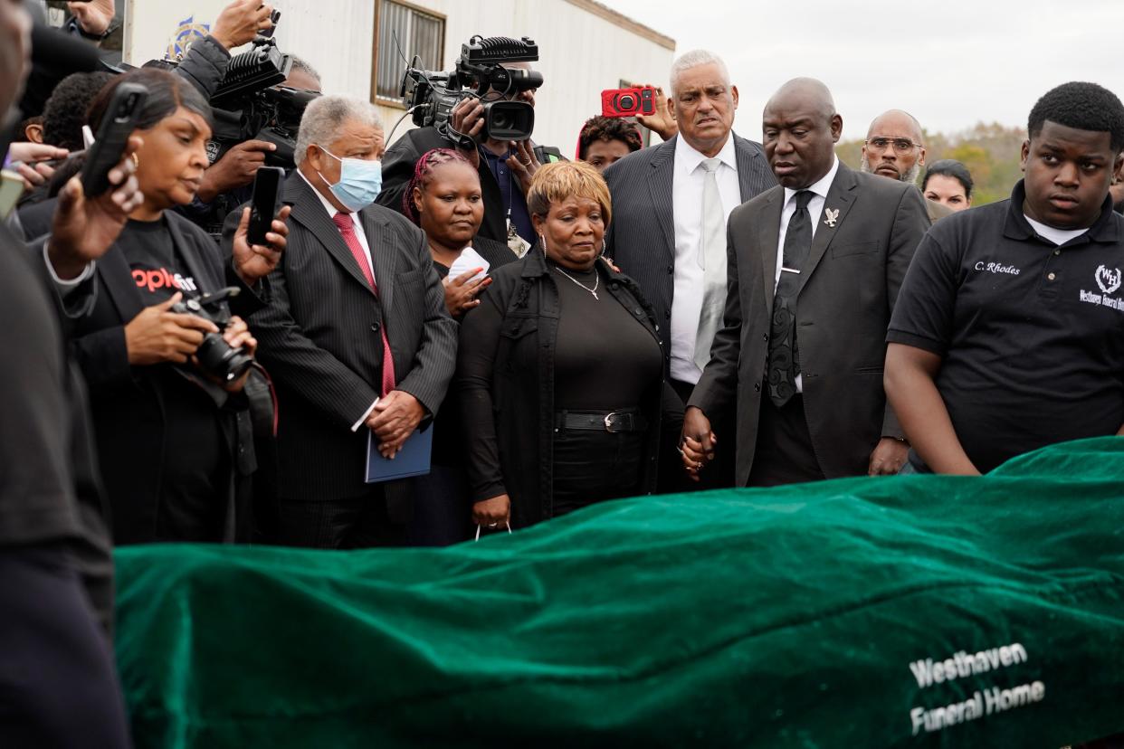 Surrounded by family members and holding hands with civil rights attorney Ben Crump, center right, Bettersten Wade, center, mother of Dexter Wade, a 37-year-old man who died after being hit by a Jackson, Miss., police SUV driven by an off-duty officer, watches her son's body transferred to a mortuary transport, after being exhumed from a pauper's cemetery near the Hinds County Penal Farm in Raymond, Monday, Nov. 13, 2023. Crump said Monday he is asking the U.S. Justice Department to investigate why authorities waited several months to notify the family of his death. (AP Photo/Rogelio V. Solis)