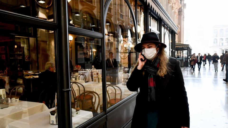 Eine Frau mit Mundschutz vor einem Restaurant in Mailand.