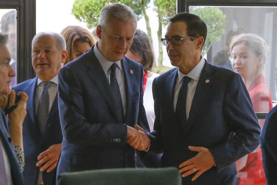 French Finance Minister Bruno Le Maire, left, shakes hands with US Treasury Secretary Steve Mnuchin next to German Finance Minister Olaf Scholz, background left, during a meeting at the G-7 Finance in Chantilly, north of Paris, on Thursday, July 18, 2019. (AP Photo/Michel Euler)