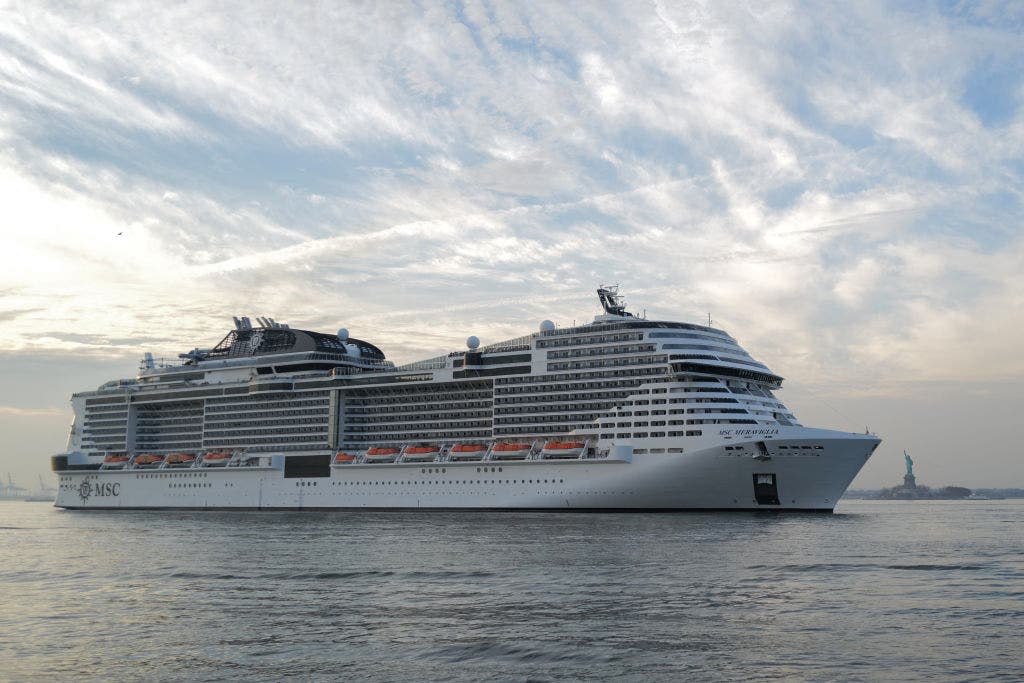 statue of liberty behind large cruise ship