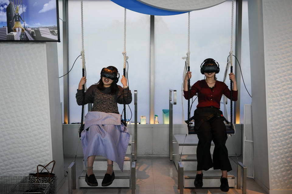 Two women wear VR headsets while playing a video game at the Sky Circus Sunshine 60 observatory Monday, Oct. 7, 2019, in Tokyo. (AP Photo/Jae C. Hong)