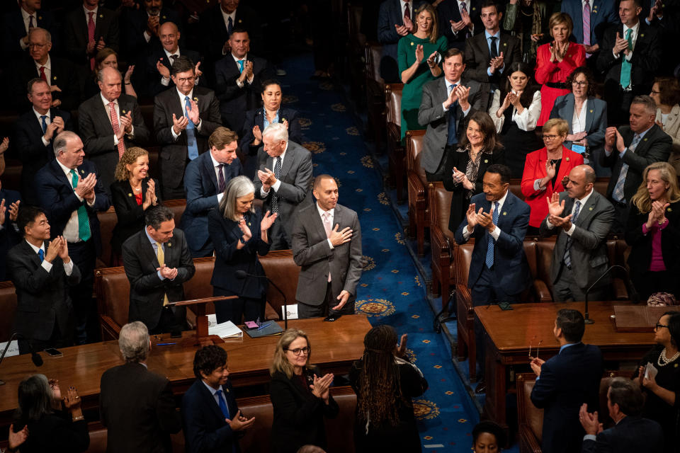 Members of the Democratic Party stand and clap for Rep. Hakeem Jeffries, who clasps his hand to his heart.