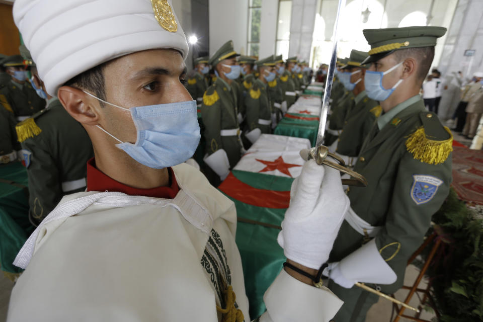 A soldier and members of the Algerian Republican Guard, guard the remains of 24 Algerians at the Moufdi-Zakaria culture palace in Algiers, Friday, July, 3, 2020. After decades in a French museum, the skulls of 24 Algerians decapitated for resisting French colonial forces were formally repatriated to Algeria in an elaborate ceremony led by the teary-eyed Algerian president. The return of the skulls was the result of years of efforts by Algerian historians, and comes amid a growing global reckoning with the legacy of colonialism. (AP Photo/Toufik Doudou)