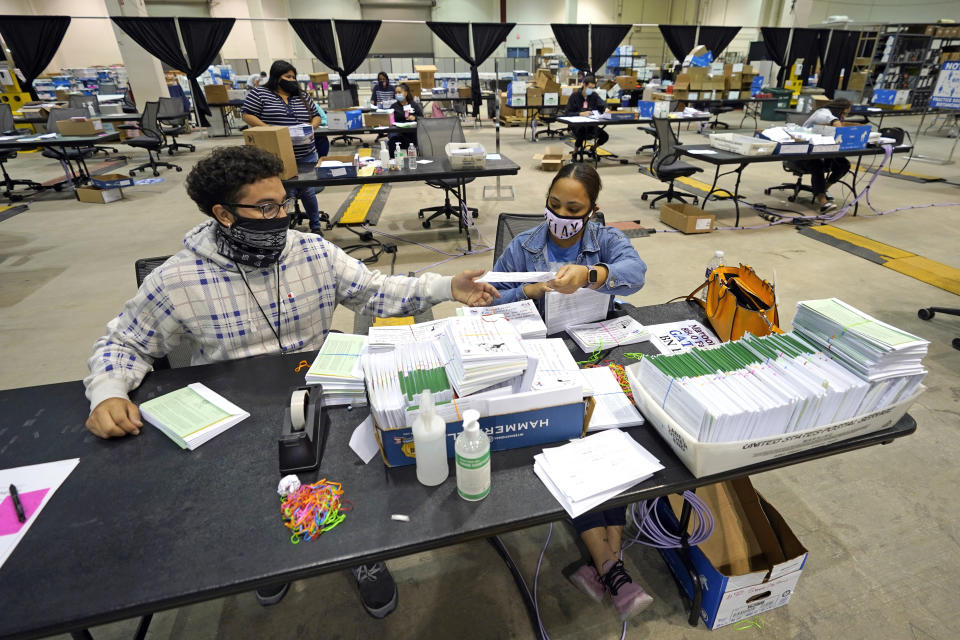 Harris County election workers Jose Vasquez, left, and Romanique Tillman prepare mail-in ballots to be sent out at election headquarters Tuesday, Sept. 29, 2020, in Houston. (AP Photo/David J. Phillip)