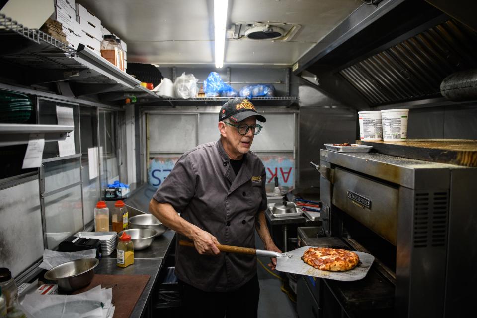 Chef David Sears pulls a pizza from the oven on The Cottage food truck in front of Paddy's Irish Public House.