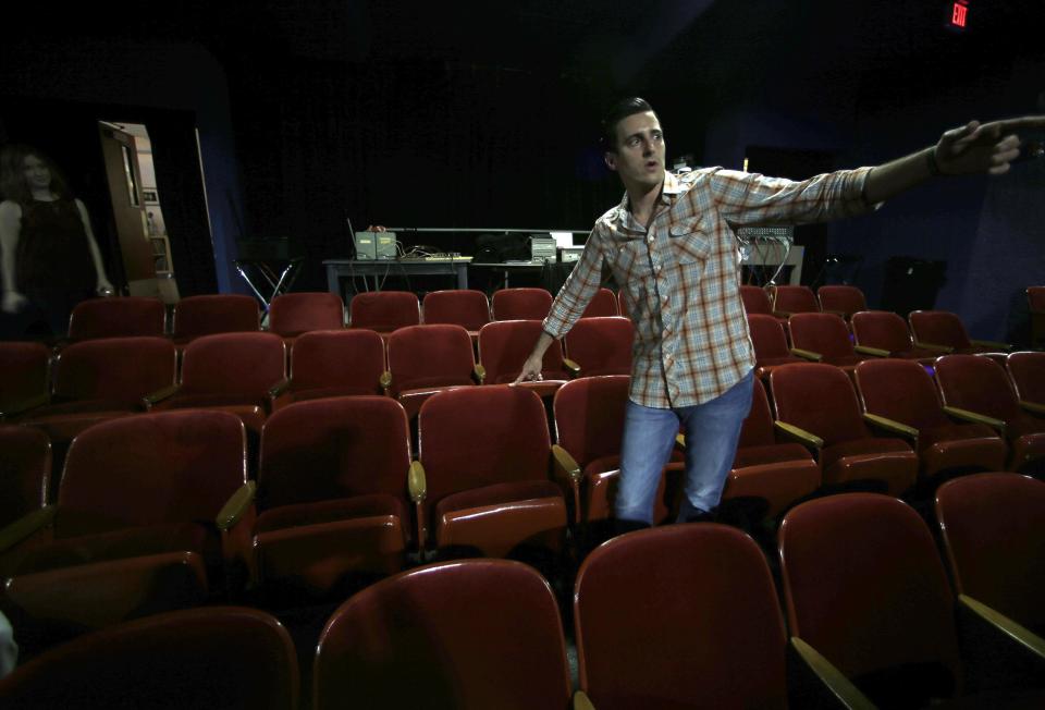 In this photo made Thursday, Oct. 31, 2013, Eric Steele, who operates the Texas Theatre, points simultaneously to the seat where Lee Harvey Oswald was sitting and the door where Dallas Police entered the theatre to arrest him in the Oak Cliff section of Dallas. Lee Harvey Oswald was arrested at the theater Nov. 22, 1963, after the assassination of President John F. Kennedy. Oswald moved a few seats to the left before police were able to take him into custody. (AP Photo/LM Otero)