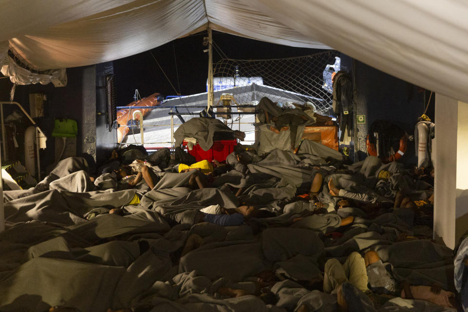 People sleep on the deck of the Sea-Watch 3 early Sunday July 24, 2022. Ships in the Mediterranean Sea have rescued over 1,100 people struggling to reach Europe in rickety smugglers boats and found five bodies. The Italian Coast Guard says Sunday that Italian vessels recovered the bodies Saturday as it rescued 674 people packed on a fishing boat adrift in the Mediterranean off the Libyan coast. (Nora Boerding/Sea-Watch via AP)