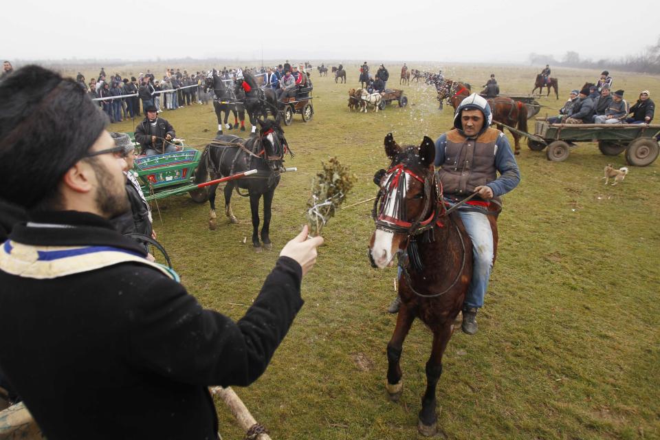 A priest blesses horses before beginning of annual race organized by Orthodox believers on Epiphany Day in Pietrosani