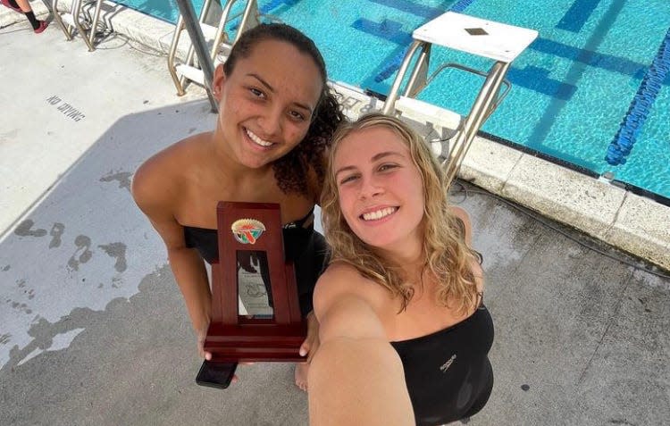 Seniors Morgan Cogle and Alexa Hansen snap a selfie with the newest addition to Jupiter swim's trophy case at Class 4A-District 5 championships on Friday in Jupiter.
