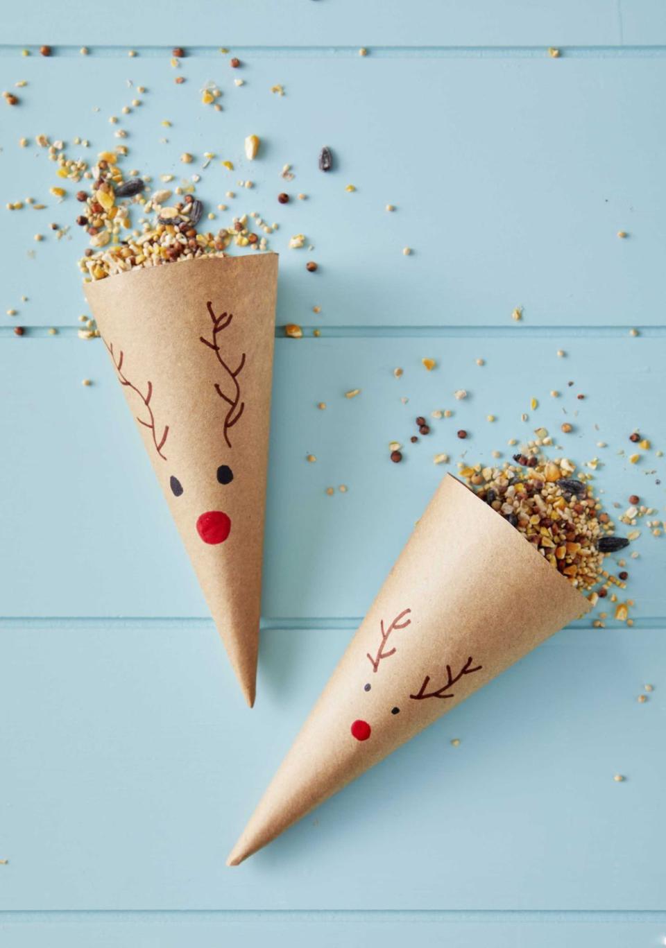 brown kraft paper cones with a reindeer face drawn on the front and filled with birdseed