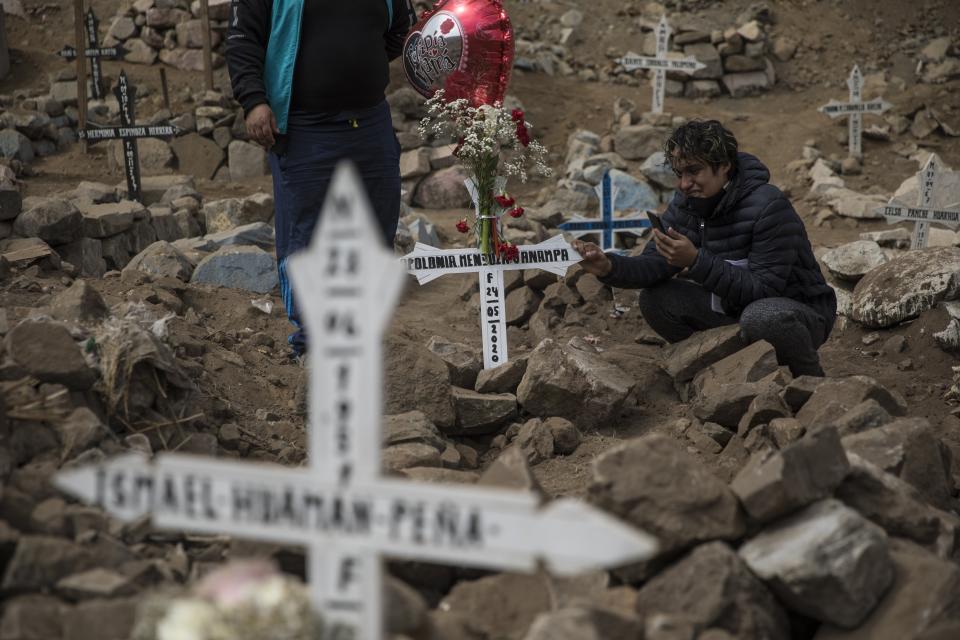 Luis Manuel llora en la tumba de su abuela Apolonia Uanampa, quien murió por el nuevo coronavirus, en el cementerio de Nueva Esperanza en las afueras de Lima, Perú, el miércoles 27 de mayo de 2020. (AP Foto/Rodrigo Abd)