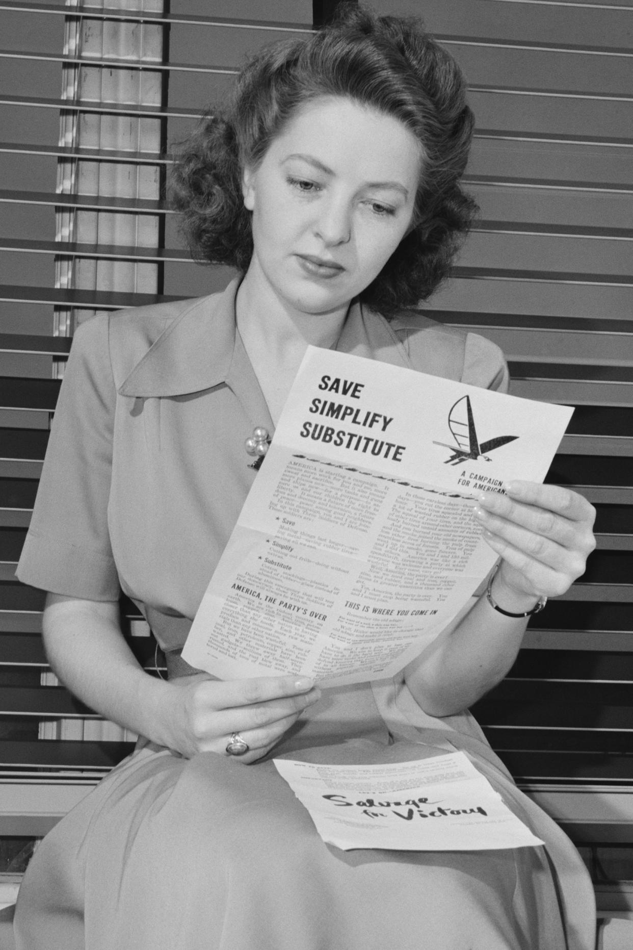 American woman reads a government brochure on titled 'Save, Simplify, Substitute' during World War 2, Feb. 1942