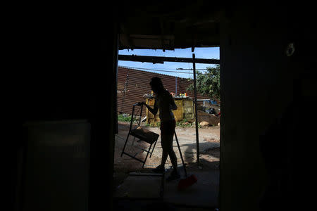 Pilar, 27, a housewife, cleans her house near a section of the fence separating Mexico and the United States, on the outskirts of Tijuana, Mexico. REUTERS/Edgard Garrido