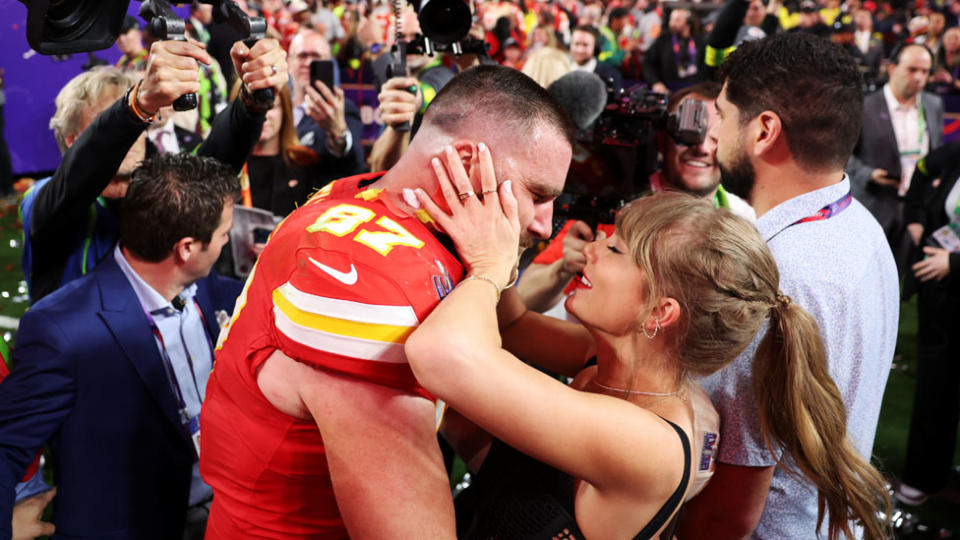 Taylor Swift and Travis Kelce embrace in the crowd.