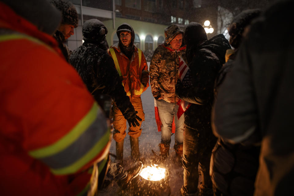 People stand around a fire during a protest against COVID-19 measures that has grown into a broader anti-government protest that continues to occupy downtown Ottawa, Ontario, on Thursday, Feb. 17, 2022. (Cole Burston/The Canadian Press via AP)