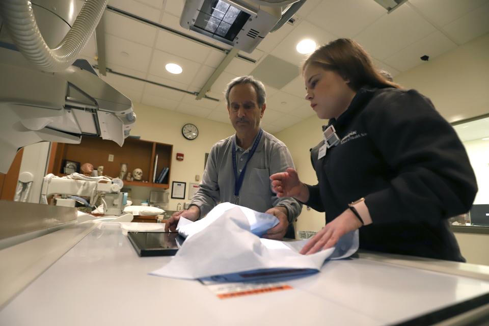 Samantha Markham, foreground, a junior radiological sciences student, and Robert Lombardo, adjunct professor of diagnostic imaging, place bone fragments underneath an x-ray machine at Quinnipiac University's Center for Medicine, Nursing and Health Sciences, Friday, Jan. 3, 2020, in North Haven, Conn. Three skeletal remains were found buried in haphazard graves underneath a home that dates back to 1790. (AP Photo/Chris Ehrmann)