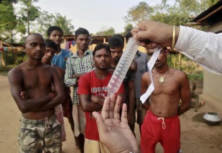 A volunteer from a non-governmental organisation (NGO) demonstrates how to use a condom to villagers during an AIDS awareness campaign on the outskirts of Agartala, India, November 6, 2015. REUTERS/Jayanta Dey