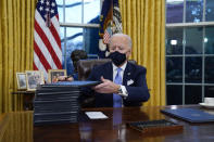 President Joe Biden signs his first executive orders in the Oval Office of the White House on Wednesday, Jan. 20, 2021, in Washington. (AP Photo/Evan Vucci)