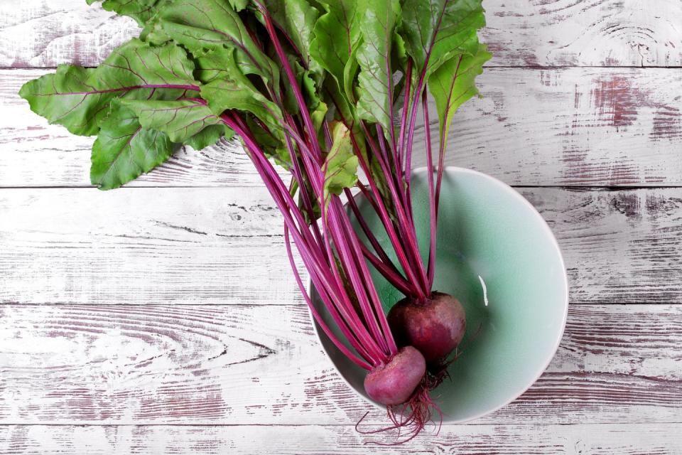 young beetroot with green tops in ceramic bowl