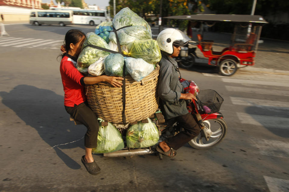 A Cambodian motor-taxi driver carries his costumer and her vegetable goods to the main market in Phnom Penh, Cambodia, Tuesday, Jan. 30, 2018. (AP Photo/Heng Sinith) 