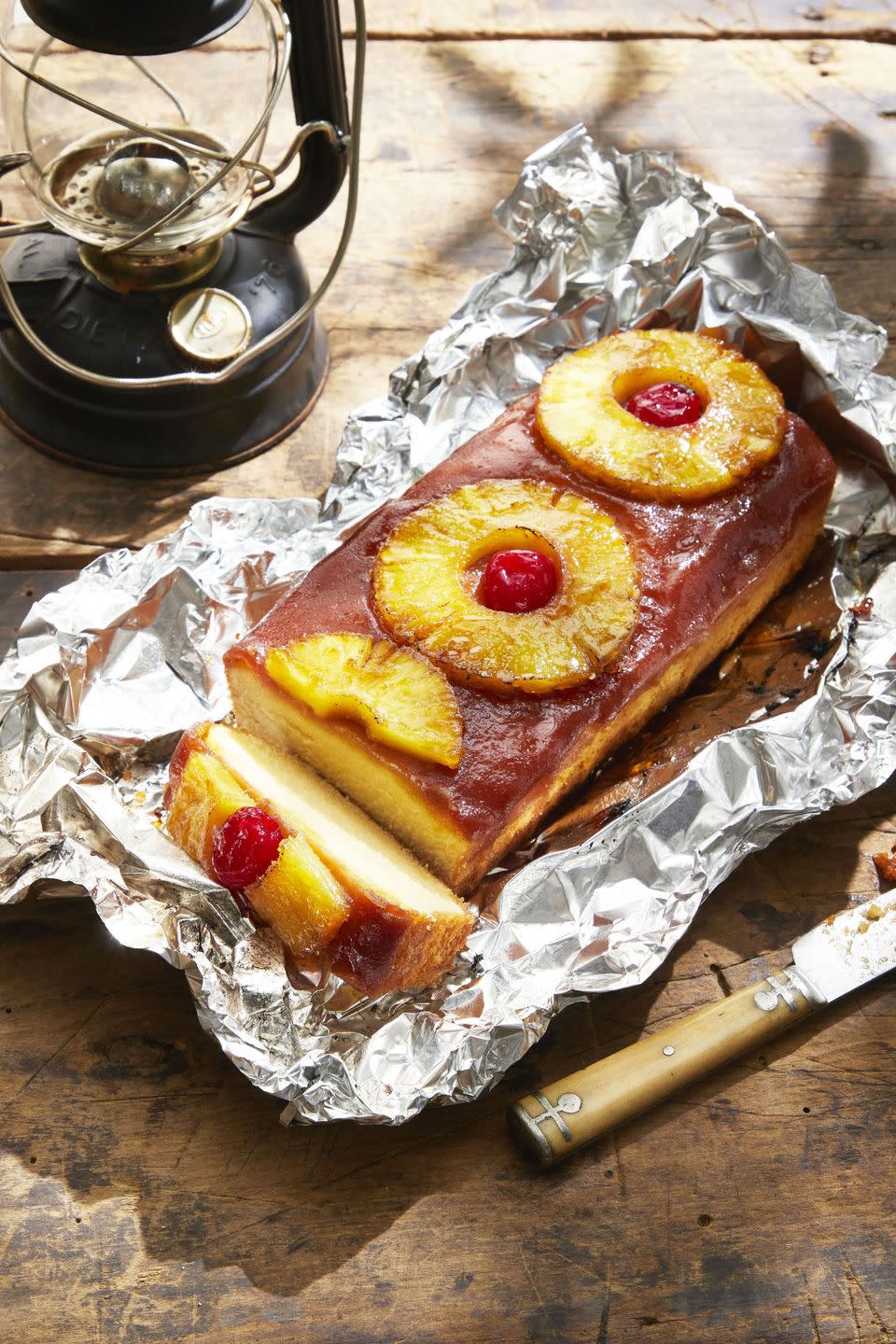 campfire grilled pineapple upside down cake on a sheet of foil on a wooden table