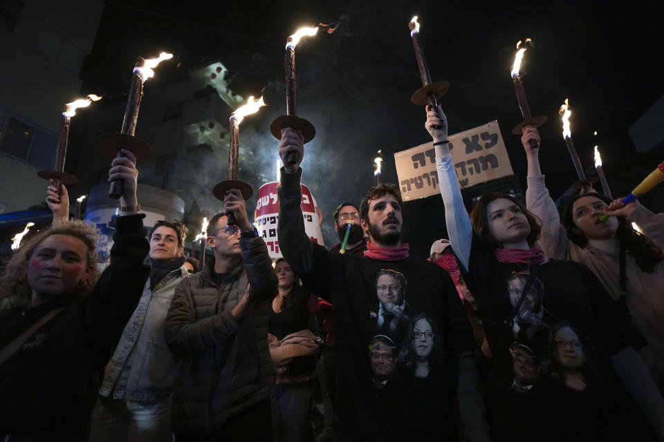 Israelis carry torches during a protest against plans by Prime Minister Benjamin Netanyahu's new government to overhaul the judicial system, in Tel Aviv, Israel, Saturday, Feb. 18, 2023. (AP Photo/Tsafrir Abayov)