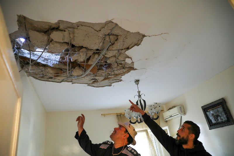 People inspect a damaged house after a shell fell on a residential area, in Abu Slim district south of Tripoli