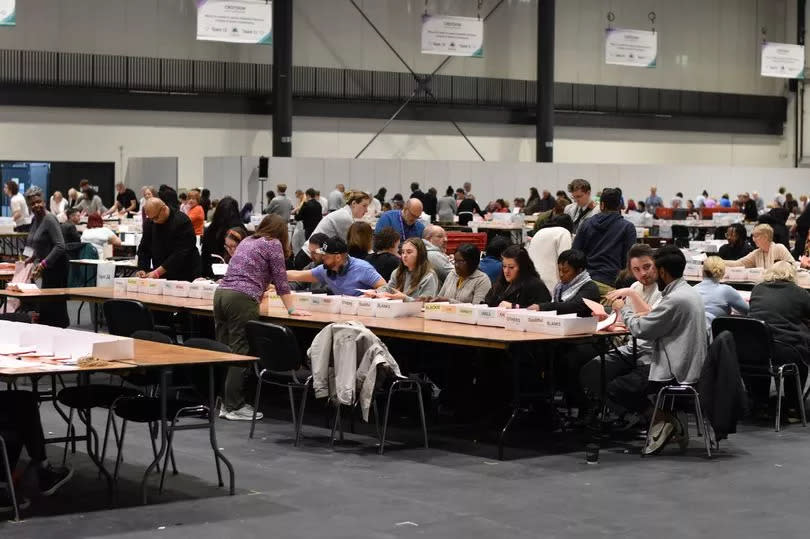 Volunteers sat in rows at tables as they start to count the votes for the Mayor of London election