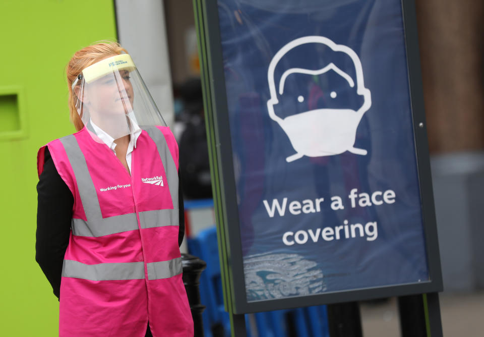 A Network Rail member of staff wearing a protective visor stands next to a sign telling commuters to wear a face covering while using public transport at Charing Cross Station, as London prepare to reopen to the public when the lifting of further lockdown restrictions in England comes into effect on Saturday. Picture date: Friday July 3, 2020.