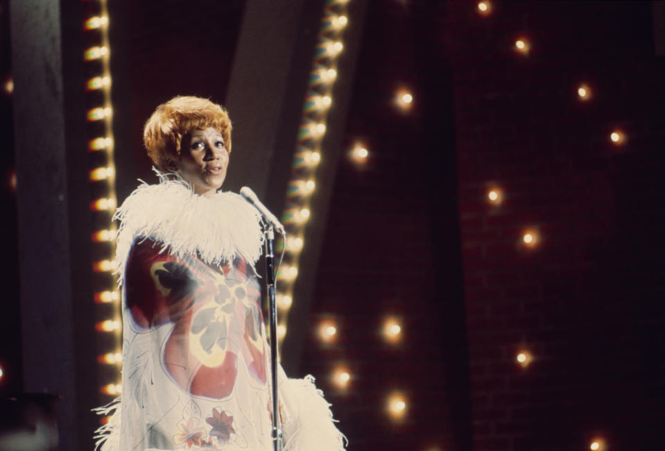 <p>Aretha Franklin live mit leuchtend orangen Haaren und einem „Flower Power“-Kleid im Stil der 70er mit weißen Federdetails am Ausschnitt und den Ärmeln. (Foto von ABC via Getty Images) </p>