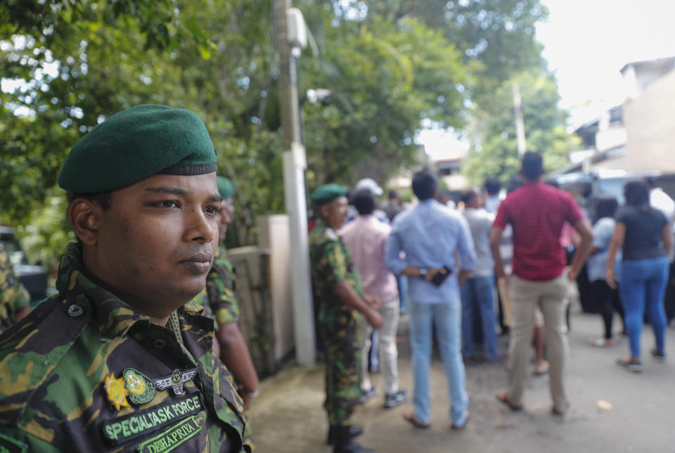 Security personnel stand guard as supporters and media personnel wait outside the residence of Sri Lanka's former defense secretary and presidential candidate Gotabaya Rajapaksa in Colombo, Sri Lanka, Sunday, Nov.17, 2019. Sri Lanka’s ruling party presidential candidate conceded defeat on Sunday to Rajapaksa, marking the return of a family revered by the Sinhalese Buddhist majority for the victory over the Tamil Tiger rebels but feared by Tamil and Muslim minorities. (AP Photo/Eranga Jayawardena)