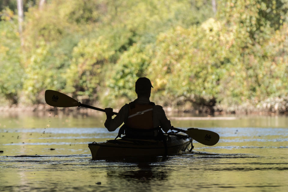 A person with a hat paddles through a body of water in Indiana Dunes Park.