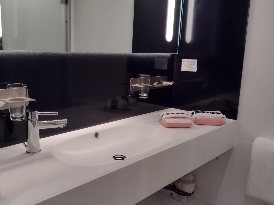A contemporary white bathroom sink with soap and towels on the counter.