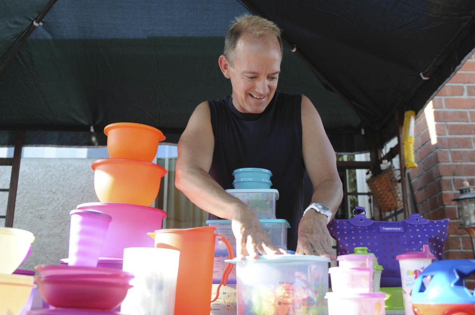 Kevin Farrell stacks some of his Tupperware products on a table while preparing for a Tupperware party in Bellflower, Calif. (AP Photo/Garrett Cheen)