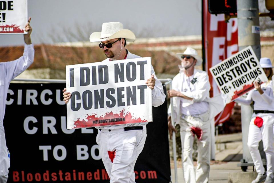 Chris Votey, a volunteer with Bloodstained Men, holds a sign toward oncoming traffic on El Paso's East Side, Thursday, March. 3.