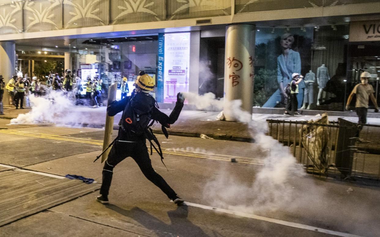 A demonstrator throws back a tear gas canister towards riot police on July 28 - Bloomberg