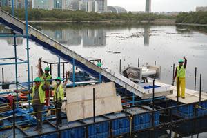 Workers celebrate completing the installation of RiverRecycle’s collector on the banks of Mithi River in Mumbai. The system aims to collect between 70 and 200 tons of river waste daily.