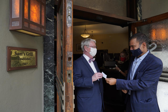 Peter Quartaroli, right, checks the vaccination card of Greg Ryken at Sam's Grill & Seafood Restaurant Friday, Aug. 20, 2021, in San Francisco. Anyone who wants to eat, drink or exercise indoors in San Francisco must show they are fully vaccinated against COVID-19 when one of the nation's most stringent restrictions on unvaccinated people takes effect Friday. (AP Photo/Eric Risberg)