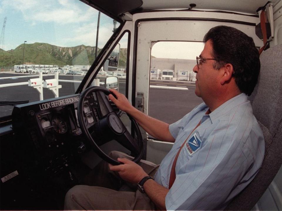 A postal worker drives a truck